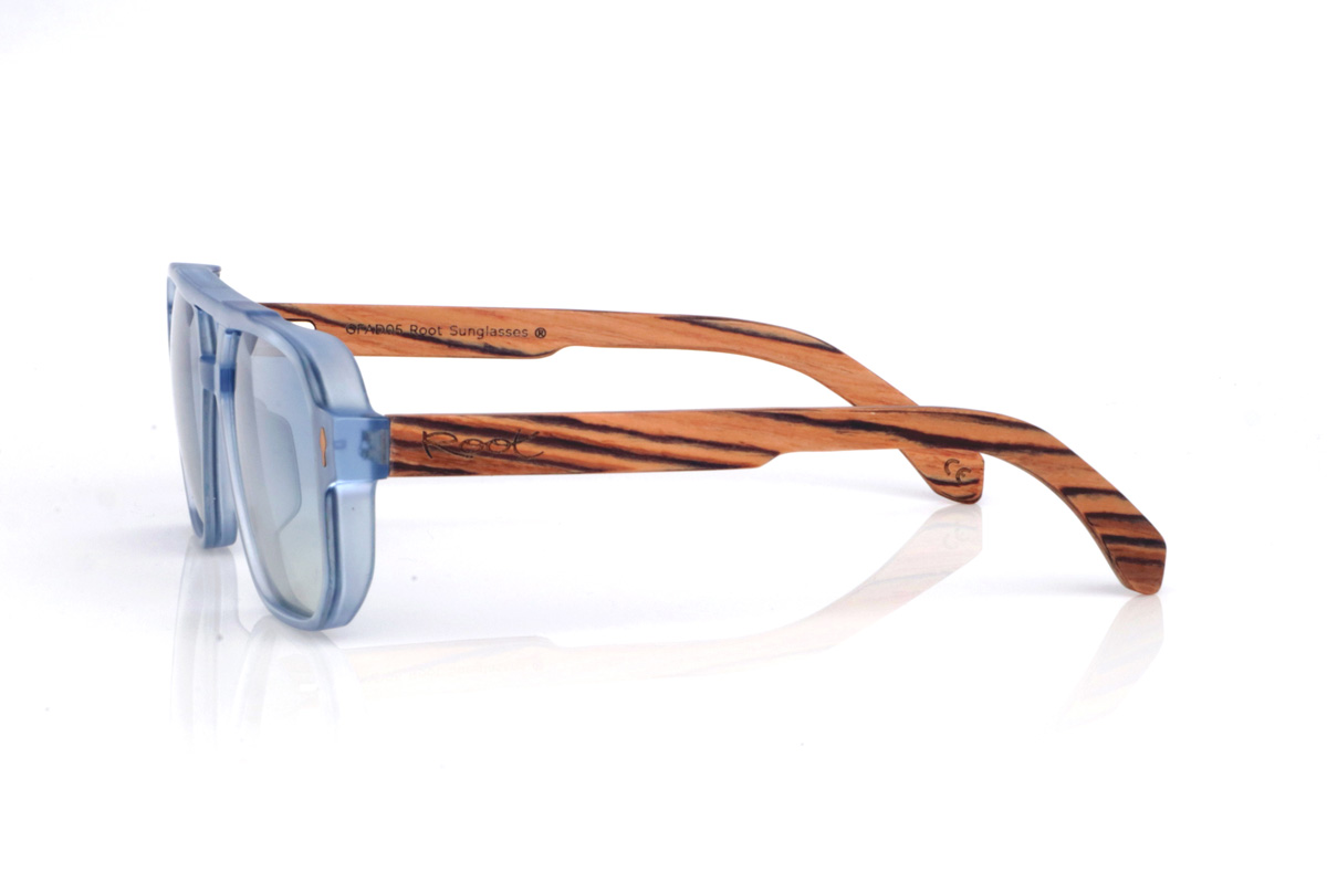 Wood eyewear of Zebrano BROOK. The wooden sunglasses BROOK combine a navigator-inspired design with bold lines and a translucent light-blue front, creating a fresh, modern look. Their zebra wood temples stand out for their high-contrast grain and natural pattern, giving the frame a handcrafted feel full of personality. The structure feels solid yet comfortable, thanks to the lightweight design and the curve of the temples, which helps maintain a stable fit for everyday wear. A modern, timeless model designed for daily use, with full UV protection.

Dimensions: 147x48 mm
Caliber: 54
 for Wholesale & Retail | Root Sunglasses® 
