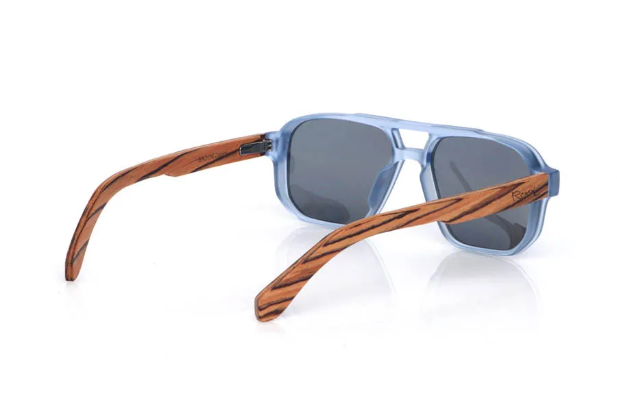 Wood eyewear of Zebrano BROOK. The wooden sunglasses BROOK combine a navigator-inspired design with bold lines and a translucent light-blue front, creating a fresh, modern look. Their zebra wood temples stand out for their high-contrast grain and natural pattern, giving the frame a handcrafted feel full of personality. The structure feels solid yet comfortable, thanks to the lightweight design and the curve of the temples, which helps maintain a stable fit for everyday wear. A modern, timeless model designed for daily use, with full UV protection.

Dimensions: 147x48 mm
Caliber: 54
 for Wholesale & Retail | Root Sunglasses® 
