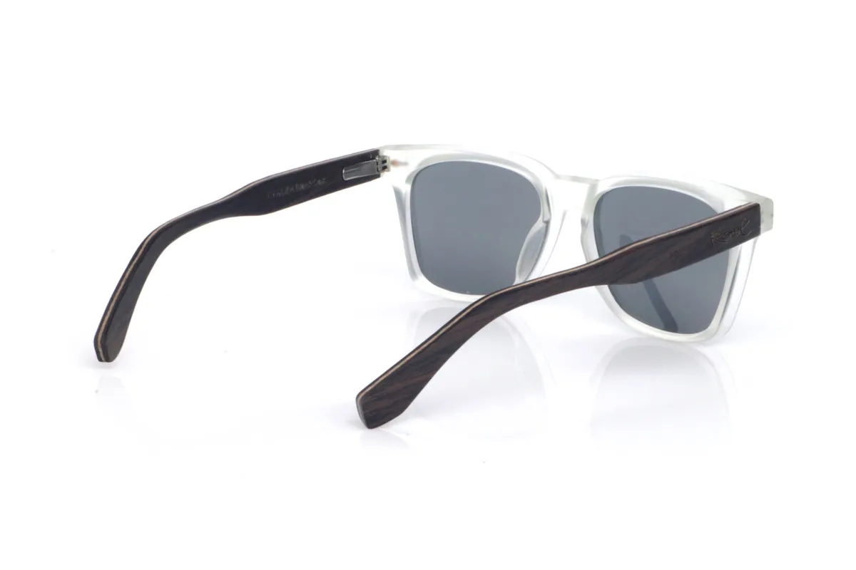 Gafas de Madera Natural de Roble CAMDEM B. Las gafas de sol de madera CAMDEM B combinan una silueta cuadrada y actual con un frontal en tono cristal translúcido, ligero y luminoso, que aporta un look muy limpio y moderno. Sus patillas de roble suman calidez y un carácter artesanal gracias a su veta natural, creando un contraste elegante con el acabado del frontal. La montura está pensada para el uso diario: es cómoda, ligera y con una curvatura de patillas que ayuda a mantener una sujeción estable. Un modelo versátil y atemporal, con protección completa frente a los rayos UV.

Dimensiones: 145x47 mm
Calibre: 52
 Venta al Por Mayor y Detalle | Root Sunglasses® 