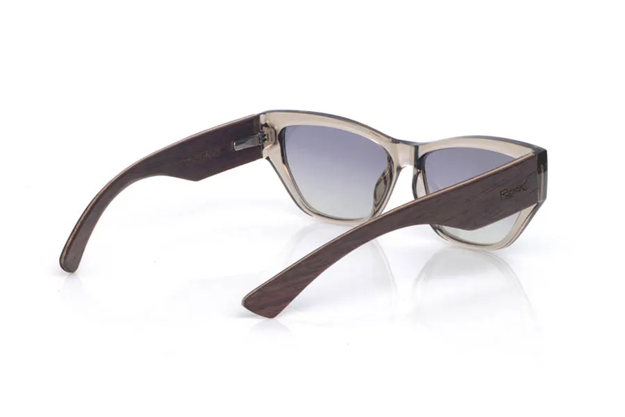 Gafas de Madera Natural de Walnut STONE. Las gafas de sol de madera STONE WALNUT mezclan un frontal translúcido en tono “smoke/stone” con una silueta ligeramente cat-eye que levanta la mirada de forma sutil. La transparencia del acetato deja ver los matices y las uniones de la montura, dándole un aire moderno y ligero.
Las patillas de nogal son protagonistas: equilibran visualmente el frontal, refuerzan la sensación de pieza sólida y bien construida, y aportan el contraste cálido de la madera con su veta natural. La curvatura de las patillas ayuda a que asienten con estabilidad y el uso resulte cómodo para el día a día, con protección completa frente a los rayos UV. 
Medidas: 145x45 Calibre: 55 Venta al Por Mayor y Detalle | Root Sunglasses® 