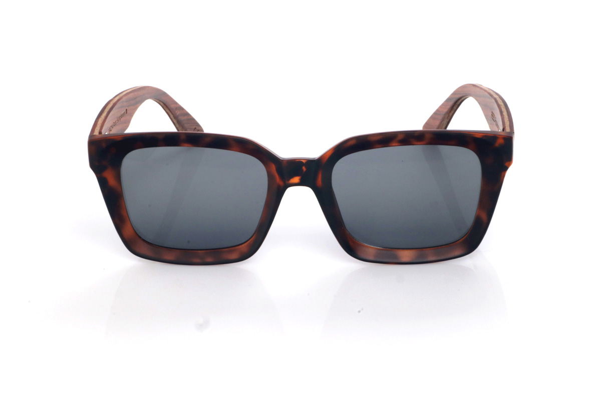 Gafas de Madera Natural de Palisandro REED. Las gafas de sol de madera REED combinan un frontal rectangular de estilo clásico con acabado efecto carey en tonos marrón y ámbar, muy fácil de llevar y con un punto elegante. El diseño tiene un contorno grueso y limpio, con una parte superior bastante recta y lentes en tono gris oscuro, que refuerzan ese look sobrio y atemporal.

Las varillas de palisandro aportan el contraste cálido de la madera natural, con una veta visible que hace que cada unidad tenga matices propios. En el lateral se aprecia el grabado de Root y una bisagra metálica integrada que suma solidez al conjunto. Un modelo cómodo y estable para uso diario, con protección completa frente a los rayos UV.

Dimensiones: 148X50MM
Calibre: 51 Venta al Por Mayor y Detalle | Root Sunglasses® 