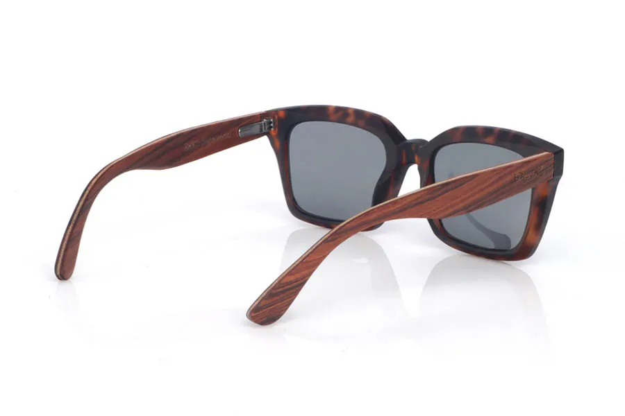 Gafas de Madera Natural de Palisandro REED. Las gafas de sol de madera REED combinan un frontal rectangular de estilo clásico con acabado efecto carey en tonos marrón y ámbar, muy fácil de llevar y con un punto elegante. El diseño tiene un contorno grueso y limpio, con una parte superior bastante recta y lentes en tono gris oscuro, que refuerzan ese look sobrio y atemporal.

Las varillas de palisandro aportan el contraste cálido de la madera natural, con una veta visible que hace que cada unidad tenga matices propios. En el lateral se aprecia el grabado de Root y una bisagra metálica integrada que suma solidez al conjunto. Un modelo cómodo y estable para uso diario, con protección completa frente a los rayos UV.

Dimensiones: 148X50MM
Calibre: 51 Venta al Por Mayor y Detalle | Root Sunglasses® 