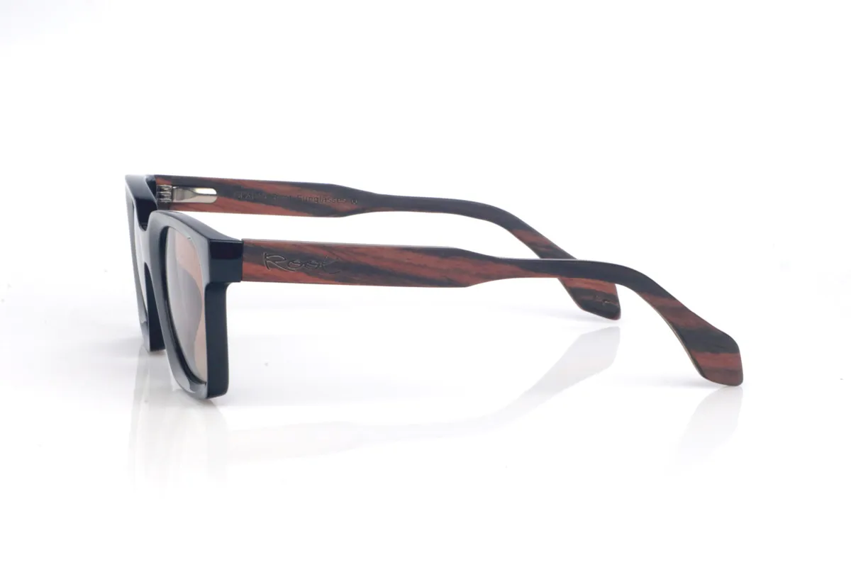 Gafas de Madera Natural de Ébano REEDUS. Las gafas de sol de madera REEDUS combinan un frontal negro profundo, de acabado brillante y líneas limpias, con una silueta rectangular de esquinas suavizadas que queda muy equilibrada en la cara. El puente tiene una curva marcada en la parte superior que le da un toque distintivo sin salir de un estilo clásico y muy ponible.  Varillas de ébano, elegantes y con veta natural visible según la pieza. Las REEDUS son un modelo cómodo, estable y muy versátil, con protección completa frente a los rayos UV.

Dimensiones: 142x47
Calibre: 47
 Venta al Por Mayor y Detalle | Root Sunglasses® 