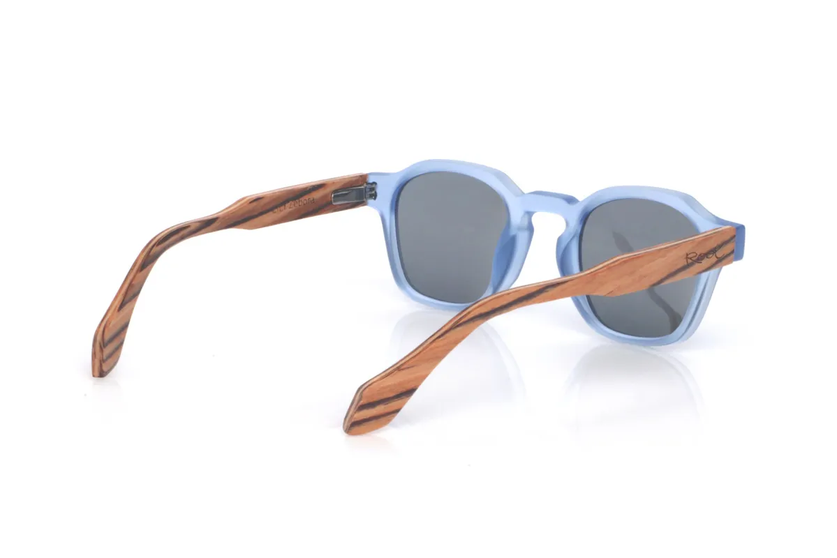 Gafas de Madera Natural de Zebrano LILY. Las gafas de sol de madera LILY combinan un frontal translúcido en azul claro, fresco y muy actual, con una silueta redondeada-ovalada de líneas suaves que resulta cómoda y muy fácil de llevar. El acabado satinado/translúcido aporta un toque ligero y luminoso, ideal para un estilo relajado con personalidad.

Las varillas de madera zebrano suman contraste y calidez gracias a su veta rayada tan característica, creando una mezcla muy original entre color y madera natural. Un modelo versátil para el día a día, con protección completa frente a los rayos UV.

Dimensiones: 144x46
Calibre: 46
 Venta al Por Mayor y Detalle | Root Sunglasses® 