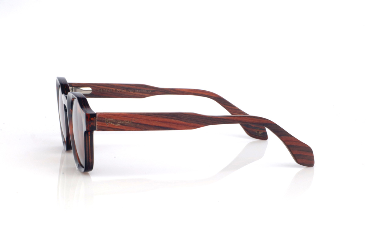 Gafas de Madera Natural de Palisandro LEAVE. Las gafas de sol de madera LEAVE combinan un frontal efecto carey en tonos cálidos, con un diseño redondeado-ovalado de líneas suaves que resulta muy equilibrado y atemporal. El puente tipo keyhole aporta un guiño clásico que le da personalidad, manteniendo un estilo fácil de llevar y muy combinable.

Las varillas de palisandro añaden un toque artesanal y elegante, con una veta natural visible que hace que cada pieza tenga matices propios. Un modelo cómodo y versátil para el día a día, con protección completa frente a los rayos UV.

Dimensiones: 144x46
Calibre: 46
 Venta al Por Mayor y Detalle | Root Sunglasses® 