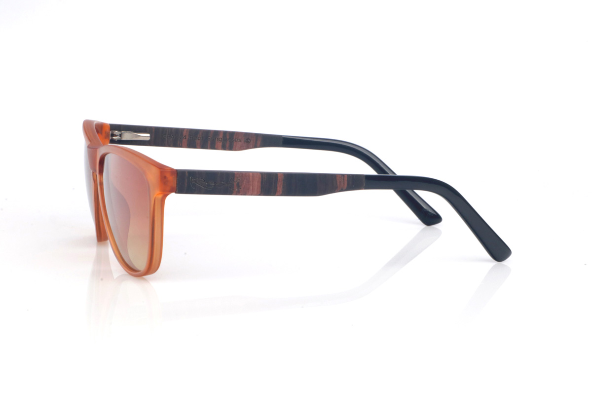Gafas de Madera Natural de Ébano DECLAN OR. Las gafas de sol de madera DECLAN OR combinan un frontal translúcido en tono ámbar, muy luminoso y con un aire retro muy actual, con una silueta suavemente envolvente que resulta cómoda y favorecedora. El diseño mantiene líneas limpias y un contorno estilizado, con una forma entre rectangular y ovalada que se adapta muy bien a distintos tipos de rostro. El puente con abertura suave añade un toque clásico sin perder ese punto moderno y veraniego.

Las varillas de ébano aportan un contraste elegante y más oscuro, con una veta vertical marcada que se aprecia en el lateral y hace que cada pieza tenga un patrón ligeramente distinto. Además, el extremo de la varilla va rematado en acetato, aportando un acabado más pulido y una sensación muy cómoda en la zona de la oreja. Un modelo versátil para el día a día, con protección completa frente a los rayos UV.

Dimensiones: 141x49
Calibre: 54
 Venta al Por Mayor y Detalle | Root Sunglasses® 