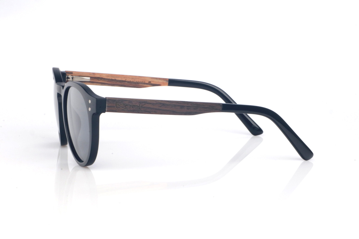 Gafas de Madera Natural de Roble SEAN B. Las gafas de sol SEAN combinan un frontal negro mate con una silueta redondeada y atemporal, equilibrada y muy fácil de llevar. El diseño destaca por su puente suavemente perfilado y un contorno limpio, con el grosor justo para dar presencia manteniendo un look ligero y moderno.

Las varillas de roble negro aportan un contraste natural y elegante, y el interior de la varilla está terminado en walnut, añadiendo un detalle cálido y un sutil efecto bicolor 

Dimensiones: 142x52 mm
Calibre: 49
 Venta al Por Mayor y Detalle | Root Sunglasses® 