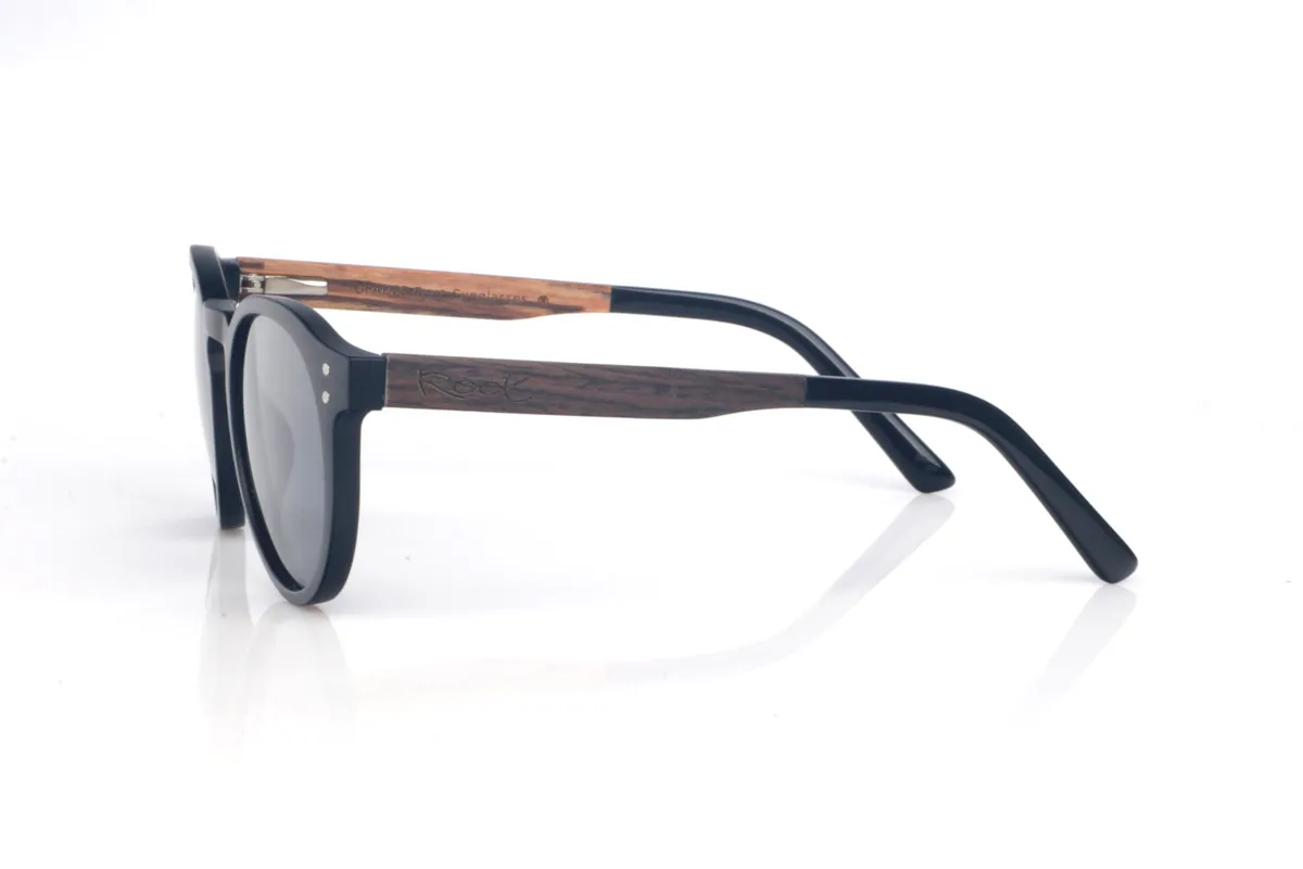 Gafas de Madera Natural de Roble SEAN B. Las gafas de sol SEAN combinan un frontal negro mate con una silueta redondeada y atemporal, equilibrada y muy fácil de llevar. El diseño destaca por su puente suavemente perfilado y un contorno limpio, con el grosor justo para dar presencia manteniendo un look ligero y moderno.

Las varillas de roble negro aportan un contraste natural y elegante, y el interior de la varilla está terminado en walnut, añadiendo un detalle cálido y un sutil efecto bicolor 

Dimensiones: 142x52 mm
Calibre: 49
 Venta al Por Mayor y Detalle | Root Sunglasses® 