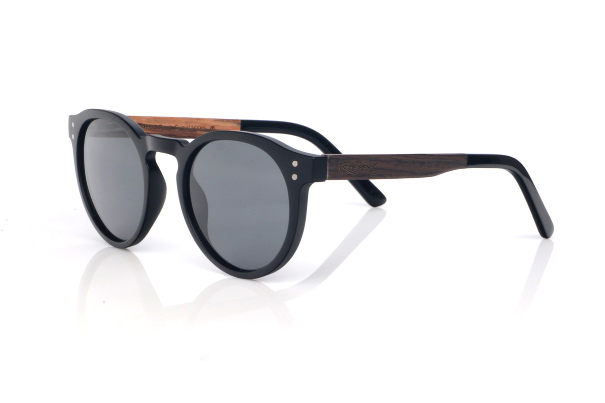 Gafas de Madera Natural de Roble SEAN B. Las gafas de sol SEAN combinan un frontal negro mate con una silueta redondeada y atemporal, equilibrada y muy fácil de llevar. El diseño destaca por su puente suavemente perfilado y un contorno limpio, con el grosor justo para dar presencia manteniendo un look ligero y moderno.

Las varillas de roble negro aportan un contraste natural y elegante, y el interior de la varilla está terminado en walnut, añadiendo un detalle cálido y un sutil efecto bicolor 

Dimensiones: 142x52 mm
Calibre: 49
 Venta al Por Mayor y Detalle | Root Sunglasses® 