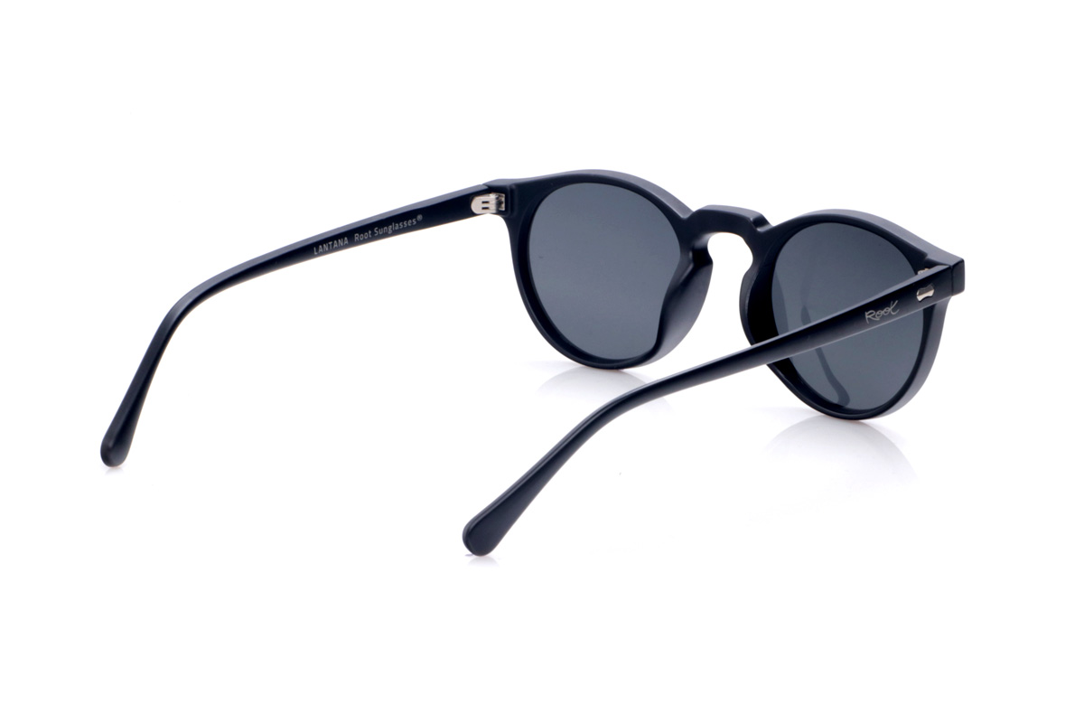 Gafas de Madera Natural de Pet LANTANA. Las gafas de sol LANTANA están fabricadas en plástico PET reciclado, transformando botellas en una montura ligera, resistente y de estilo contemporáneo. Su forma redondeada con puente tipo “keyhole” aporta un aire clásico muy favorecedor, fácil de combinar tanto en looks urbanos como más relajados. La montura negra mate enfatiza las líneas limpias del diseño y resalta los pequeños detalles metálicos del frontal y las varillas, reforzando su carácter moderno y sostenible. Las varillas finas y ligeramente curvadas se adaptan cómodamente a la cabeza, ofreciendo un ajuste estable durante todo el día. Equipadas con lentes polarizadas de alta calidad, las LANTANA reducen los reflejos y protegen tus ojos frente a los rayos UV, convirtiéndose en unas gafas recicladas ideales para quienes buscan un básico unisex con mucha personalidad y compromiso con el planeta. Dimensiones: 138x47mm. Calibre: 48 Venta al Por Mayor y Detalle | Root Sunglasses® 