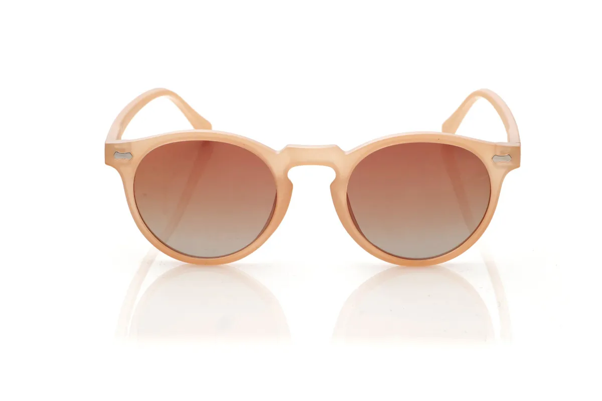 Wood eyewear of Pet KENTIA. KENTIA sunglasses are made from recycled PET plastic, giving bottles a new life and transforming them into lightweight, durable frames with a modern style. Their rounded shape with a keyhole bridge softens facial features and adds a fresh, casual look, perfect for everyday wear. The translucent finish in a soft, warm tone allows a glimpse of the frame's interior, reinforcing its personality and sustainable essence. Small metallic details on the front and temples add a distinctive touch without disrupting the design's harmony. The thin, curved temples fit comfortably on the head, ensuring a secure fit for hours. Equipped with high-quality polarized lenses, KENTIA sunglasses reduce glare and protect your eyes from UV rays, making them ideal recycled sunglasses for those seeking style, comfort, and respect for the planet all in one. Dimensions: 139 x 48 mm. Lens width: 48 mm. for Wholesale & Retail | Root Sunglasses® 