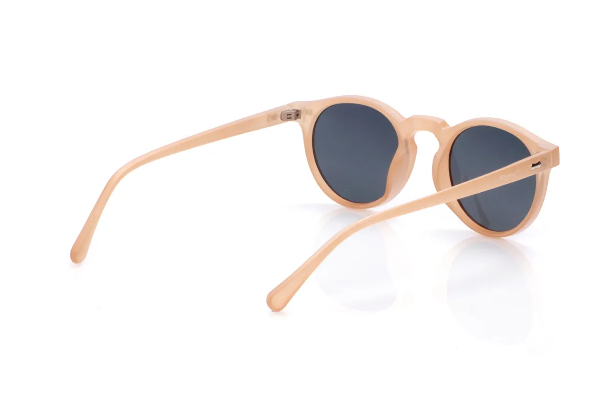 Wood eyewear of Pet KENTIA. KENTIA sunglasses are made from recycled PET plastic, giving bottles a new life and transforming them into lightweight, durable frames with a modern style. Their rounded shape with a keyhole bridge softens facial features and adds a fresh, casual look, perfect for everyday wear. The translucent finish in a soft, warm tone allows a glimpse of the frame's interior, reinforcing its personality and sustainable essence. Small metallic details on the front and temples add a distinctive touch without disrupting the design's harmony. The thin, curved temples fit comfortably on the head, ensuring a secure fit for hours. Equipped with high-quality polarized lenses, KENTIA sunglasses reduce glare and protect your eyes from UV rays, making them ideal recycled sunglasses for those seeking style, comfort, and respect for the planet all in one. Dimensions: 139 x 48 mm. Lens width: 48 mm. for Wholesale & Retail | Root Sunglasses® 