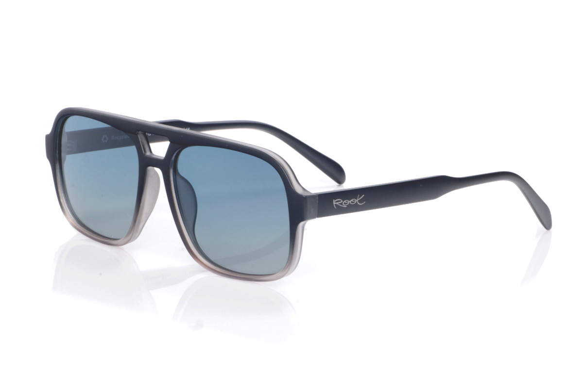 Gafas de Madera Natural de Pet modelo ATNES. Las gafas de sol ATNES están fabricadas en plástico PET reciclado, dando una segunda vida a las botellas para convertirlas en unas gafas ligeras, resistentes y con un marcado carácter urbano. Su diseño de inspiración aviador, con forma rectangular suavemente redondeada y puente recortado, aporta un aire retro-deportivo muy favorecedor en rostros medios y anchos. La montura presenta un elegante degradado que va del negro sólido en la parte superior a un gris transparente en la zona inferior, creando un efecto moderno que resalta las líneas del frontal. Las varillas, en negro mate, son anchas y de curvatura suave para ajustarse cómodamente y ofrecer buena estabilidad durante todo el día. Equipadas con lentes polarizadas de alta calidad, las ATNES reducen los reflejos y protegen eficazmente frente a los rayos UV, convirtiéndose en una opción unisex perfecta para quienes buscan gafas recicladas con estilo potente, confort y conciencia medioambiental. Dimensiones: 149x54mm; Calibre 57
 | Root Sunglasses® 
