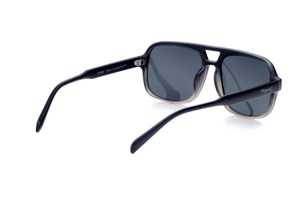 Gafas de Madera Natural de Pet ATNES. Las gafas de sol ATNES están fabricadas en plástico PET reciclado, dando una segunda vida a las botellas para convertirlas en unas gafas ligeras, resistentes y con un marcado carácter urbano. Su diseño de inspiración aviador, con forma rectangular suavemente redondeada y puente recortado, aporta un aire retro-deportivo muy favorecedor en rostros medios y anchos. La montura presenta un elegante degradado que va del negro sólido en la parte superior a un gris transparente en la zona inferior, creando un efecto moderno que resalta las líneas del frontal. Las varillas, en negro mate, son anchas y de curvatura suave para ajustarse cómodamente y ofrecer buena estabilidad durante todo el día. Equipadas con lentes polarizadas de alta calidad, las ATNES reducen los reflejos y protegen eficazmente frente a los rayos UV, convirtiéndose en una opción unisex perfecta para quienes buscan gafas recicladas con estilo potente, confort y conciencia medioambiental. Dimensiones: 149x54mm; Calibre 57
 Venta al Por Mayor y Detalle | Root Sunglasses® 