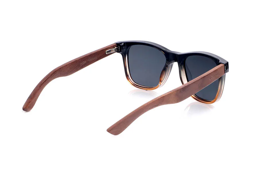 Wood eyewear of Walnut DION. The <b>DION</b> sunglasses combine a black acetate front with an amber gradient at the bottom and walnut wood temples, creating a warm and contemporary contrast. Their classic wayfarer-inspired shape flatters most faces, while the small metal accents on the front add an urban and elegant touch. The natural grain of the walnut makes each pair unique, and thanks to their lightness and gently curved temples, they are comfortable to wear all day. They feature polarized gradient lenses that reduce glare and provide effective UV protection. Measurements: 145 x 49 mm. Lens width: 51 mm. for Wholesale & Retail | Root Sunglasses® 
