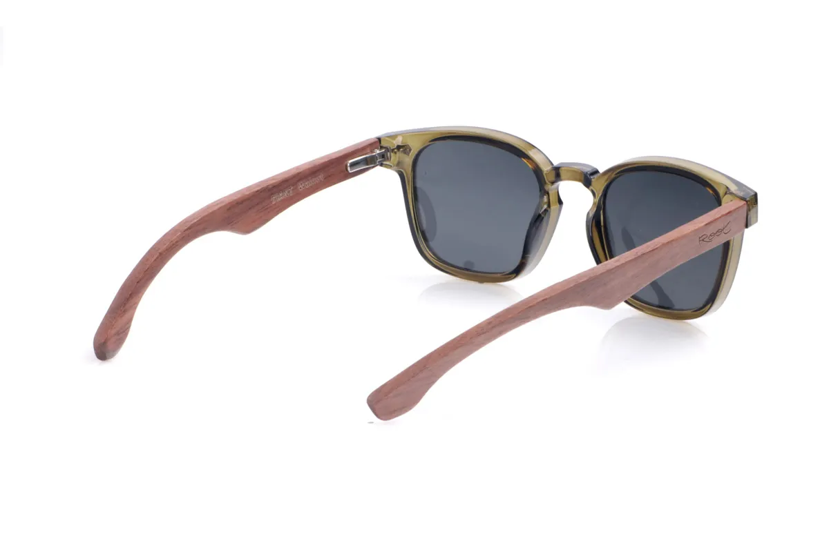 Gafas de Madera Natural de Walnut DIANT W. Las gafas de sol <b>DIANT W</b> combinan un frontal translúcido en tono verde oliva con varillas de madera de nogal, creando un contraste elegante y muy natural. Su forma ligeramente cuadrada con puente marcado favorece rostros medianos y aporta un aire moderno y desenfadado, mientras que los pequeños apliques metálicos del frontal añaden un toque de detalle sin recargar el diseño. Las varillas de nogal, de líneas finas y curvatura suave, muestran las vetas de la madera y ofrecen un ajuste cómodo para el uso diario. Equipadas con lentes polarizadas que reducen los reflejos y protegen eficazmente frente a los rayos UV, son una opción perfecta para quienes buscan estilo y sostenibilidad en la misma gafa. Medidas: 142x48 mm. Calibre 47.
 Venta al Por Mayor y Detalle | Root Sunglasses® 