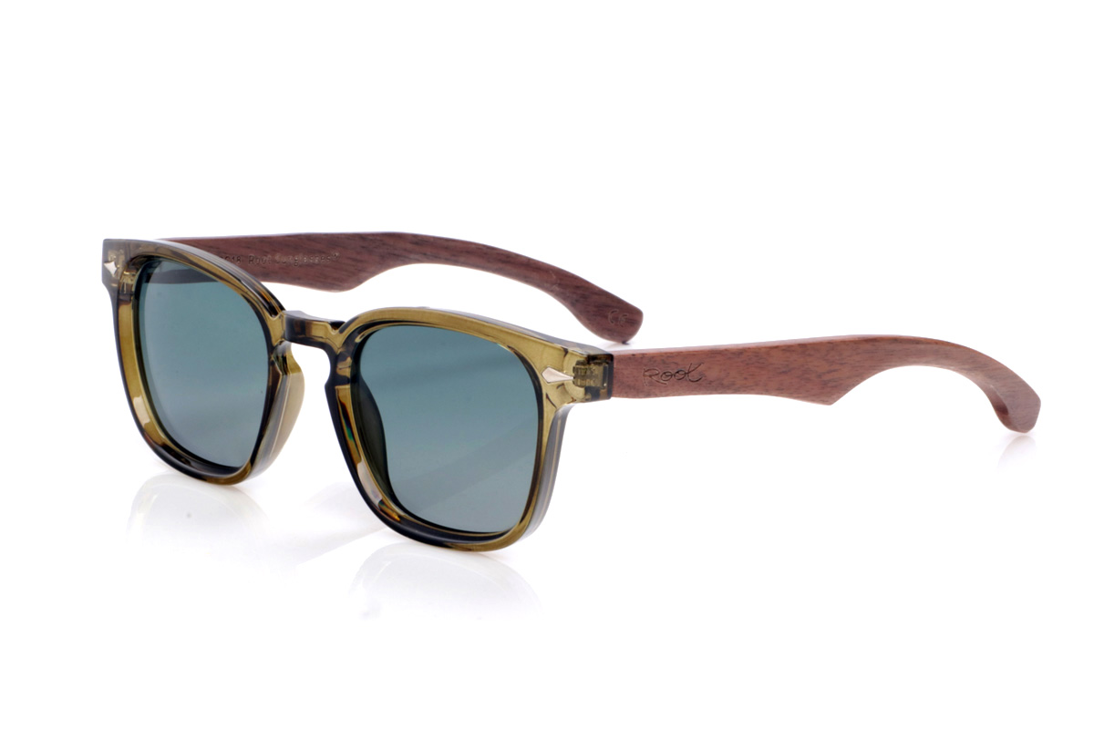 Gafas de Madera Natural de Walnut modelo DIANT W. Las gafas de sol <b>DIANT W</b> combinan un frontal translúcido en tono verde oliva con varillas de madera de nogal, creando un contraste elegante y muy natural. Su forma ligeramente cuadrada con puente marcado favorece rostros medianos y aporta un aire moderno y desenfadado, mientras que los pequeños apliques metálicos del frontal añaden un toque de detalle sin recargar el diseño. Las varillas de nogal, de líneas finas y curvatura suave, muestran las vetas de la madera y ofrecen un ajuste cómodo para el uso diario. Equipadas con lentes polarizadas que reducen los reflejos y protegen eficazmente frente a los rayos UV, son una opción perfecta para quienes buscan estilo y sostenibilidad en la misma gafa. Medidas: 142x48 mm. Calibre 47.
 | Root Sunglasses® 