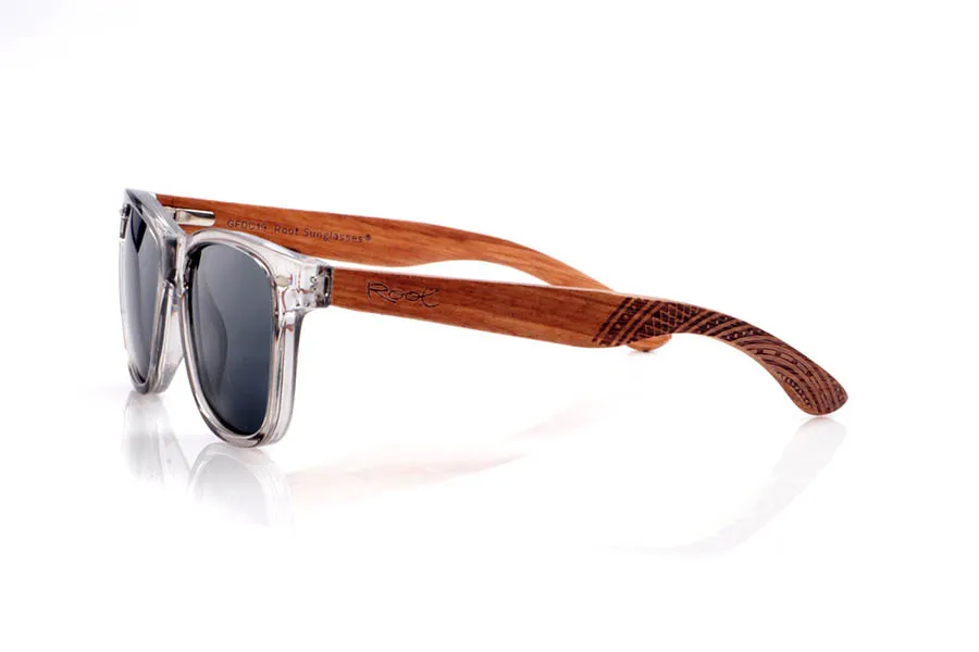Gafas de Madera Natural de Zebrano MARLIN. Las gafas de sol <b>MARLIN</b> combinan un frontal transparente gris ahumado con varillas de madera de zebrano, que muestran vetas cálidas y naturales y rematan en unas puntas curvadas con grabado geométrico de inspiración étnica. La montura, de líneas rectas y puente marcado, mantiene una silueta clásica tipo wayfarer reinterpretada en clave ligera y contemporánea, mientras que las lentes polarizadas reducen los reflejos y ofrecen una protección eficaz frente a los rayos UV, convirtiéndolas en una opción cómoda y muy versátil para el día a día. Medidas: 143x49 mm. Calibre 50.
 Venta al Por Mayor y Detalle | Root Sunglasses® 