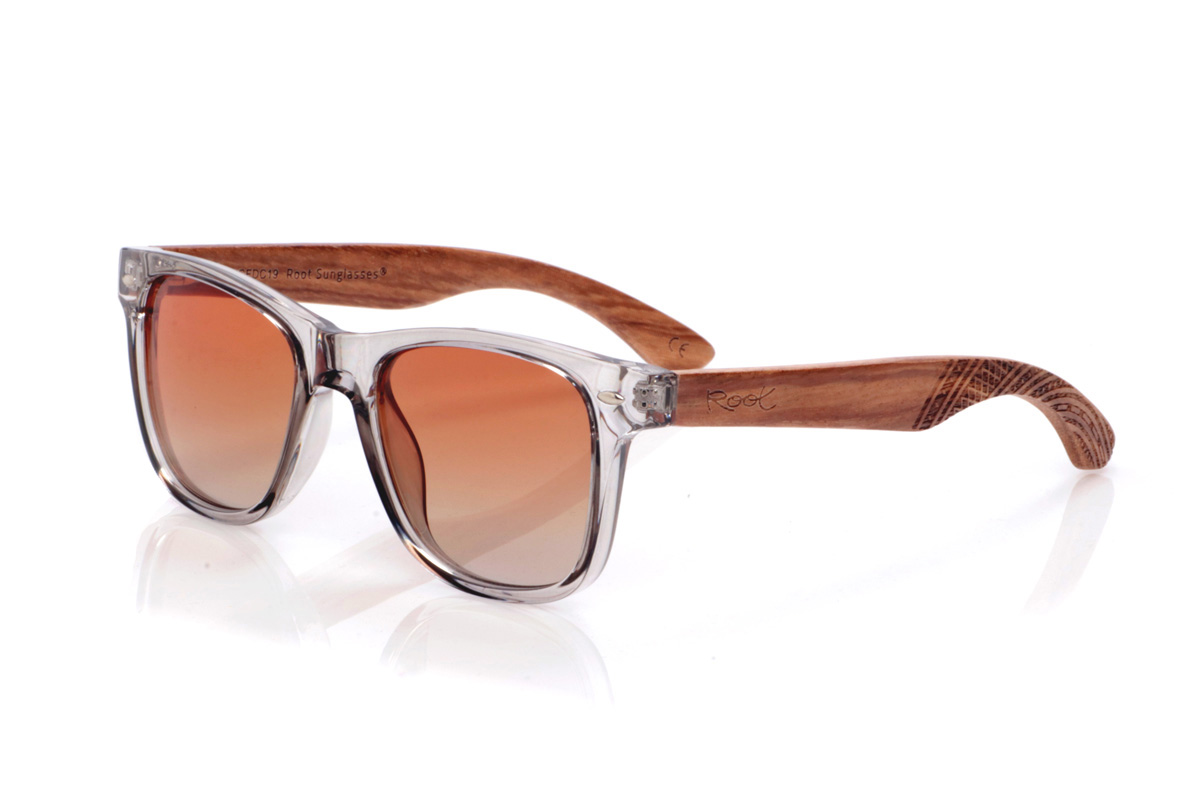 Wood eyewear of Zebrano modelo MARLIN. The MARLIN sunglasses combine a transparent, smoky gray front with zebrawood temples that showcase warm, natural grain and are finished with curved tips featuring an ethnic-inspired geometric engraving. The frame, with its straight lines and prominent bridge, maintains a classic wayfarer silhouette reinterpreted with a light and contemporary touch, while the polarized lenses reduce glare and offer effective UV protection, making them a comfortable and versatile choice for everyday wear. Measurements: 143 x 49 mm. Lens width: 50. | Root Sunglasses® 