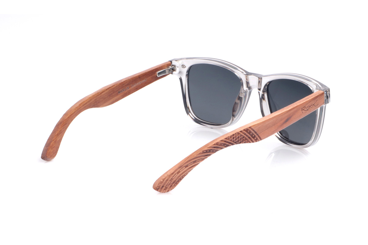 Wood eyewear of Zebrano MARLIN. The MARLIN sunglasses combine a transparent, smoky gray front with zebrawood temples that showcase warm, natural grain and are finished with curved tips featuring an ethnic-inspired geometric engraving. The frame, with its straight lines and prominent bridge, maintains a classic wayfarer silhouette reinterpreted with a light and contemporary touch, while the polarized lenses reduce glare and offer effective UV protection, making them a comfortable and versatile choice for everyday wear. Measurements: 143 x 49 mm. Lens width: 50. for Wholesale & Retail | Root Sunglasses® 