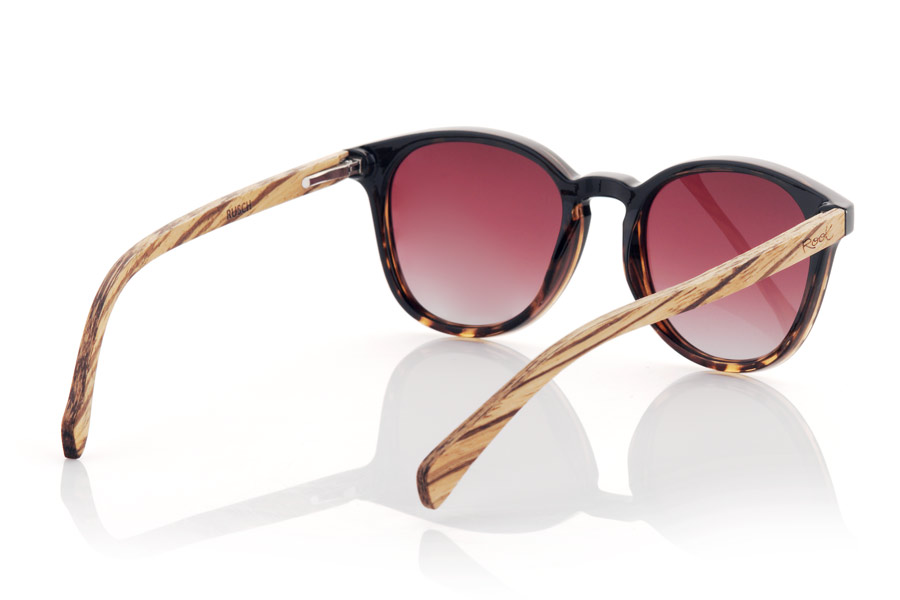 Wood eyewear of Walnut RUSCH. RUSCH glasses are the perfect choice for those looking for an elegant and timeless style. With a two-tone black and black tortoiseshell front, these glasses have a distinctive touch that makes them unique. The walnut wood temples add a touch of warmth and naturalness to its design. This rounded model is unisex and adapts to any face shape, making it perfect for anyone. In addition, the gradient lenses give them a very special touch and provide total protection against UV rays and sunlight, which makes them an excellent option for any outdoor activity. Front Measurement: for Wholesale & Retail | Root Sunglasses® 