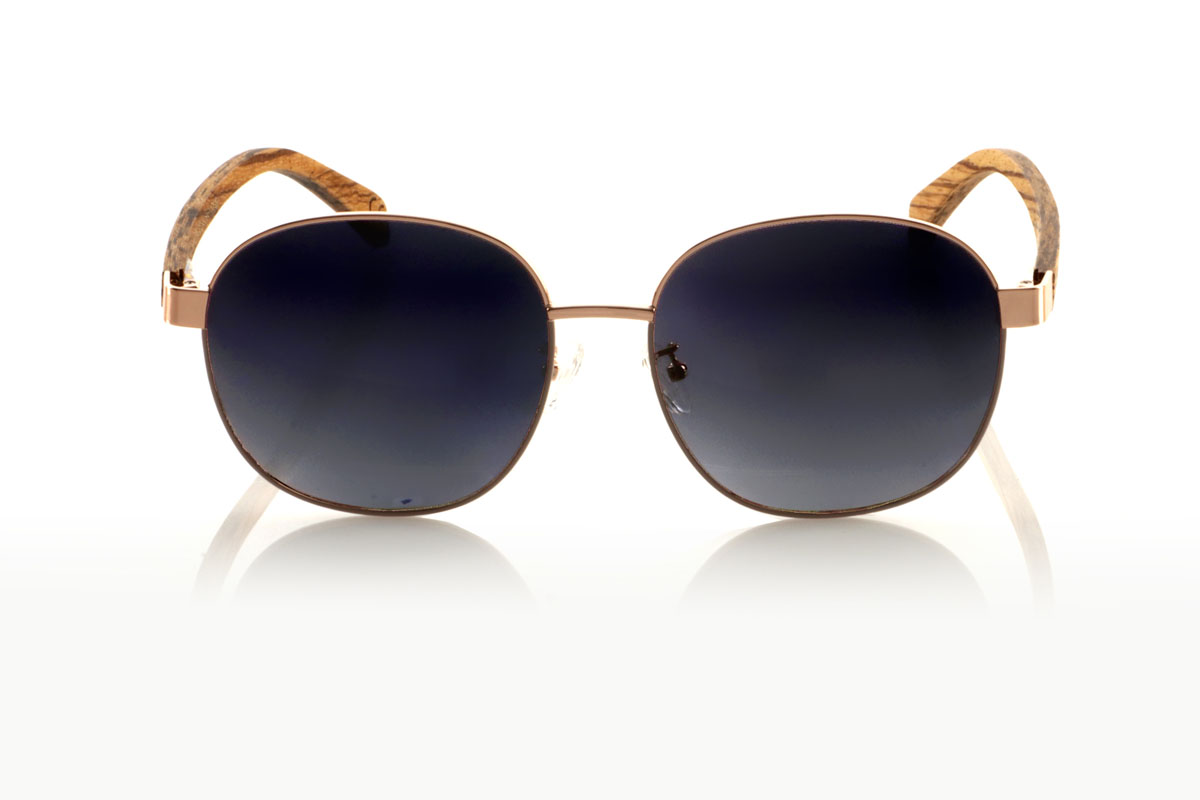 Gafas de Madera Natural de Zebrano CHLOE. Las gafas de sol CHLOE son la definición de versatilidad y estilo atemporal. Este modelo unisex fusiona una montura metálica fina en color bronce, evocando un toque vintage, con varillas de madera de zebra que añaden un contraste natural y moderno. La combinación resulta en unas gafas que se adaptan tanto a looks clásicos como contemporáneos, perfectas para cualquier persona que aprecie la elegancia y la calidad. Con una medida de 156x54mm y un calibre de 58, las CHLOE ofrecen un ajuste cómodo y amplia protección visual. Prepárate para destacar con este diseño único, que promete convertirse en un imprescindible en tu colección Venta al Por Mayor y Detalle | Root Sunglasses® 