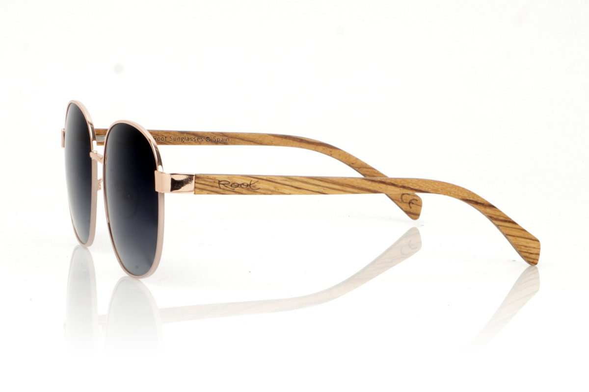 Wood eyewear of Zebrano CHLOE. CHLOE sunglasses are the definition of versatility and timeless style. This unisex model fuses a thin metal frame in bronze, evoking a vintage touch, with zebra wood temples that add a natural and modern contrast. The combination results in glasses that adapt to both classic and contemporary looks, perfect for anyone who appreciates elegance and quality. Measuring 156x54mm and with a caliber of 58, the CHLOE offers a comfortable fit and ample visual protection. Get ready to stand out with this unique design, which promises to become a must-have in your collection. for Wholesale & Retail | Root Sunglasses® 