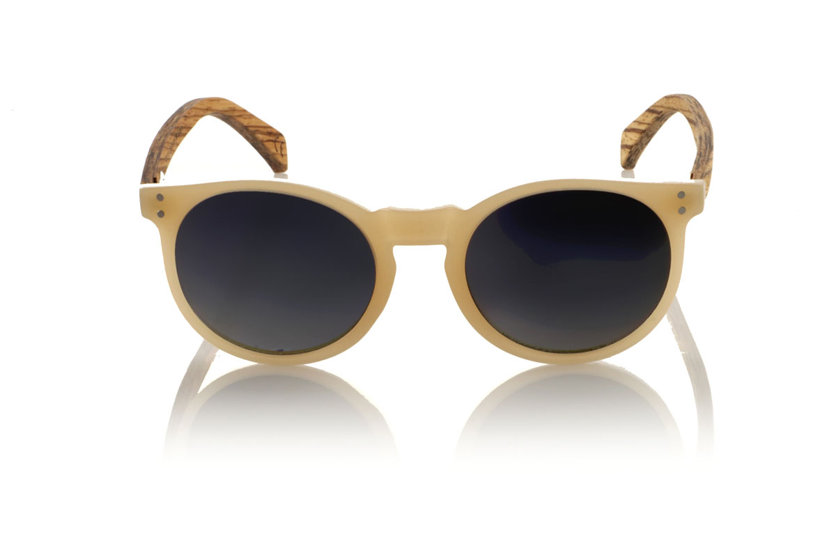 Gafas de Madera Natural de Zebrano INKY. Las gafas de sol INKY capturan la esencia de un diseño delicado y femenino con su forma redondeada y tamaño más pequeño. La montura en un sofisticado marfil brillo satinado ofrece un toque de luz y elegancia, mientras que las varillas de madera de zebrano introducen un contraste natural y llamativo. Este modelo es ideal para aquellas que buscan unas gafas distintivas pero sutiles, que complementen sin sobrecargar. Con medidas de 138x48mm y un calibre de 47, las INKY se adaptan perfectamente a rostros más finos, asegurando comodidad y estilo. Sumérgete en la belleza de los detalles para realzar tu mirada con un encanto único. Venta al Por Mayor y Detalle | Root Sunglasses® 