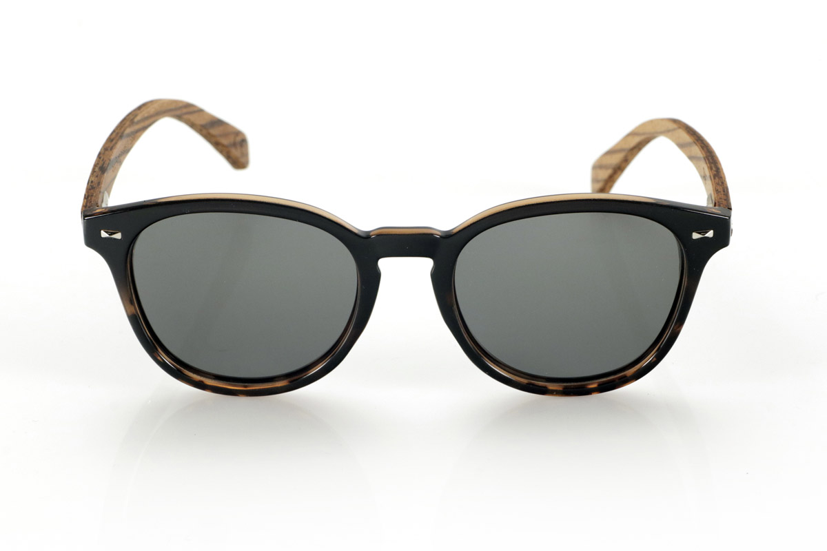 Wood eyewear of Zebrano TANE. TANE wooden sunglasses fuse classic and artisanal. Their vintage-inspired frames in Carey acetate provide a sophisticated and versatile style, while their Zebrano wood temples provide a warm and organic character, highlighting the natural beauty of the material. Thanks to their rounded and timeless design, these glasses adapt to a wide variety of faces, offering a balanced look with a touch of personality. Their high-quality polarized lenses guarantee total protection against UV rays, providing visual comfort in any environment.
Dimensions 142x52mm. Caliber 50, for Wholesale & Retail | Root Sunglasses® 