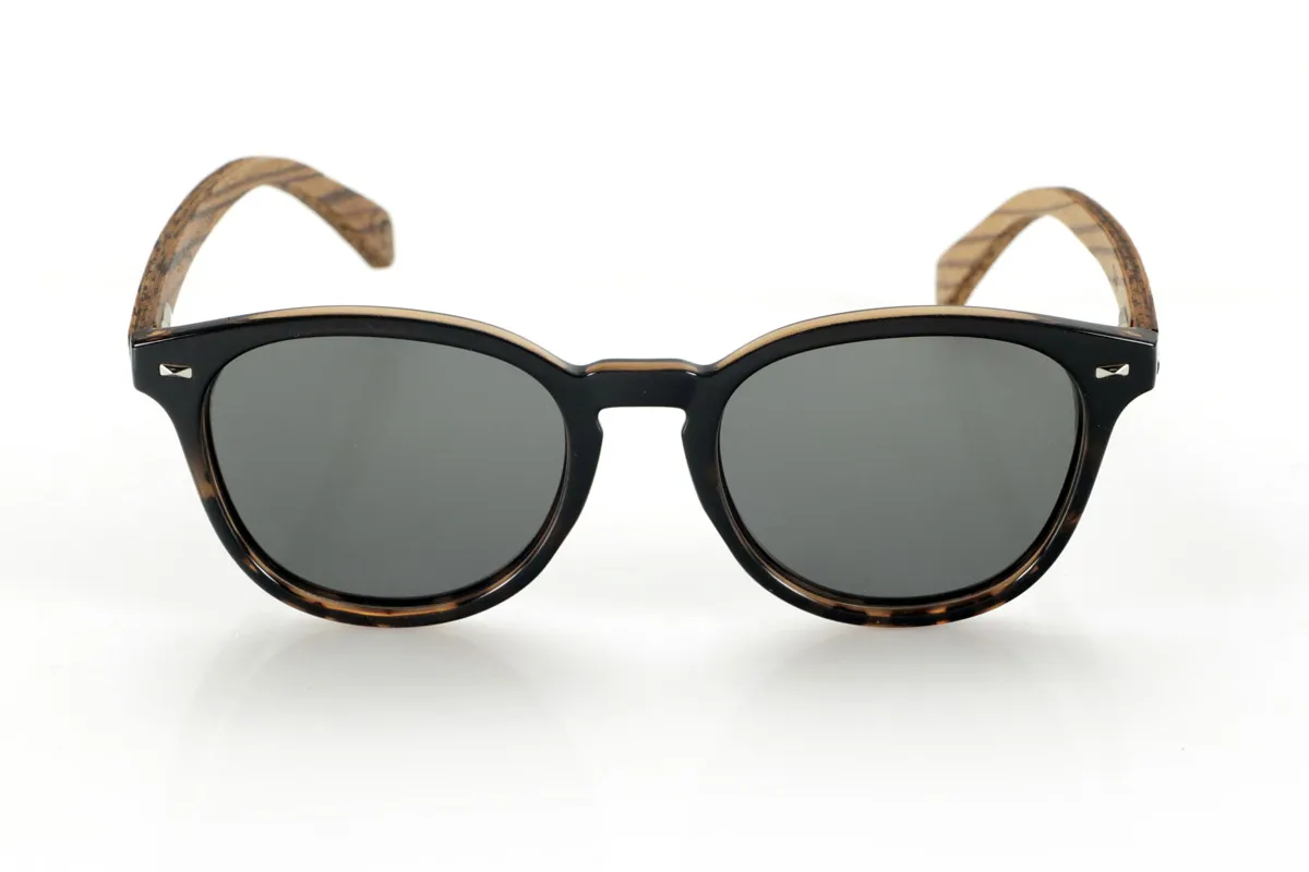 Gafas de Madera Natural de Zebrano TANE. Las gafas de madera TANE fusionan lo clásico y lo artesanal. Su montura de inspiración vintage en acetato Carey aporta un estilo sofisticado y versátil, mientras que sus varillas de madera de Zebrano aportan un carácter cálido y orgánico, resaltando la belleza natural del material. Gracias a su diseño redondeado y atemporal, estas gafas se adaptan a una gran variedad de rostros, ofreciendo un look equilibrado con un toque de personalidad. Sus lentes polarizadas de alta calidad garantizan protección total contra los rayos UV, aportando comodidad visual en cualquier entorno.
Dimensiones de 142x52mm. Calibre de 50, Venta al Por Mayor y Detalle | Root Sunglasses® 