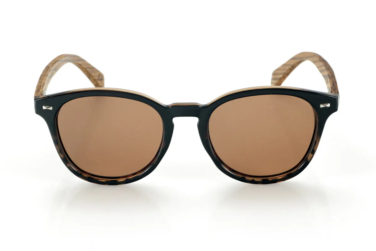 Gafas de Madera Natural de Zebrano TANE. Las gafas de madera TANE fusionan lo clásico y lo artesanal. Su montura de inspiración vintage en acetato Carey aporta un estilo sofisticado y versátil, mientras que sus varillas de madera de Zebrano aportan un carácter cálido y orgánico, resaltando la belleza natural del material. Gracias a su diseño redondeado y atemporal, estas gafas se adaptan a una gran variedad de rostros, ofreciendo un look equilibrado con un toque de personalidad. Sus lentes polarizadas de alta calidad garantizan protección total contra los rayos UV, aportando comodidad visual en cualquier entorno.
Dimensiones de 142x52mm. Calibre de 50, Venta al Por Mayor y Detalle | Root Sunglasses® 