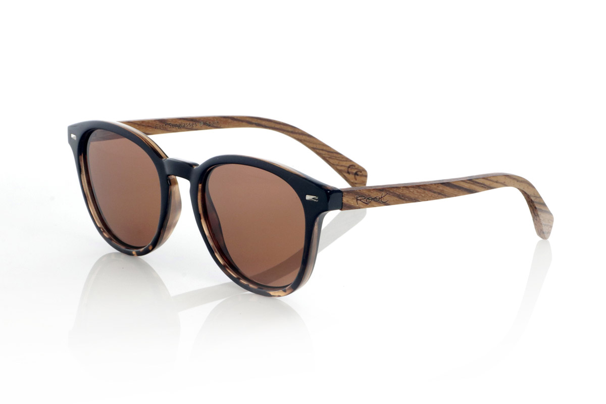 Wood eyewear of Zebrano TANE. TANE wooden sunglasses fuse classic and artisanal. Their vintage-inspired frames in Carey acetate provide a sophisticated and versatile style, while their Zebrano wood temples provide a warm and organic character, highlighting the natural beauty of the material. Thanks to their rounded and timeless design, these glasses adapt to a wide variety of faces, offering a balanced look with a touch of personality. Their high-quality polarized lenses guarantee total protection against UV rays, providing visual comfort in any environment.
Dimensions 142x52mm. Caliber 50, for Wholesale & Retail | Root Sunglasses® 