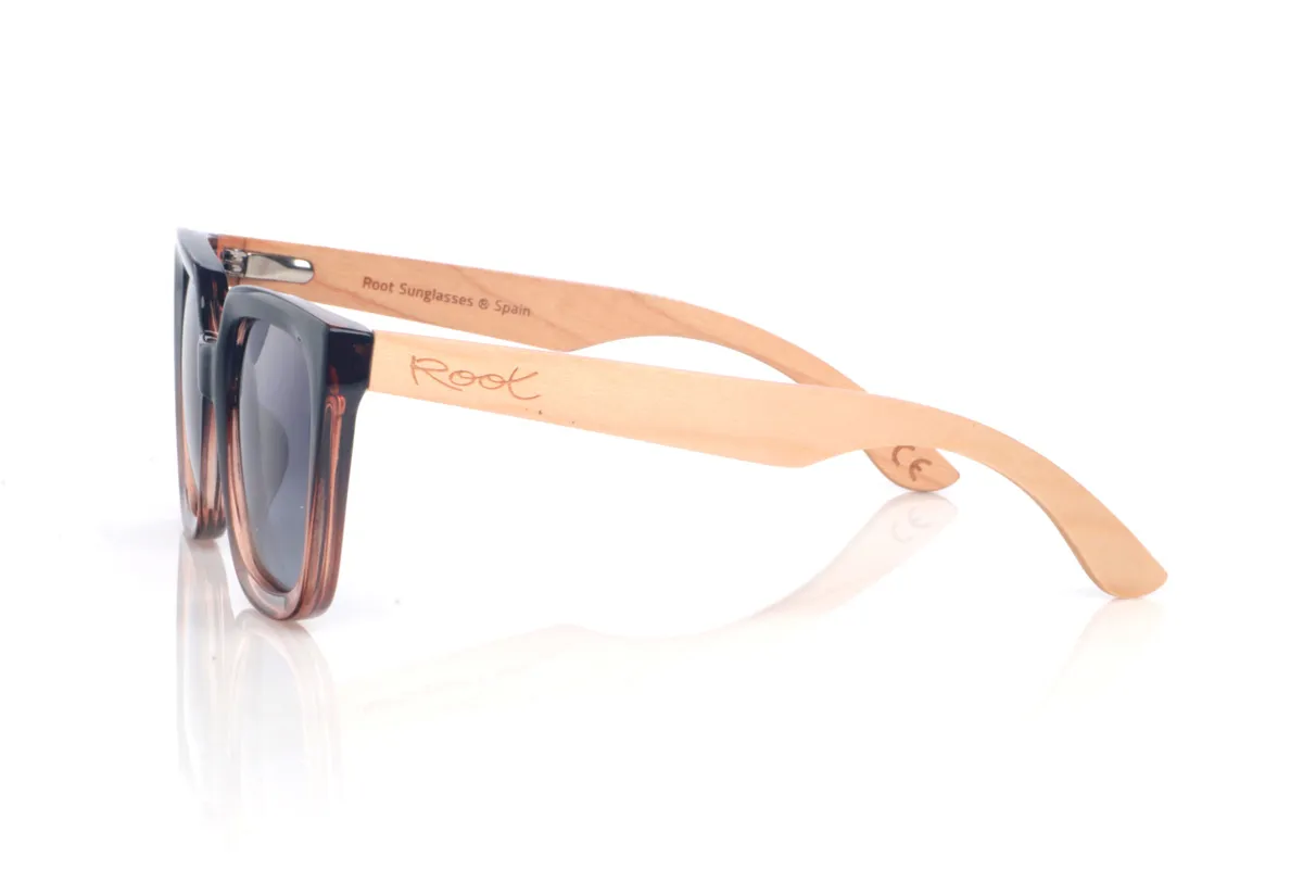 Wood eyewear of Maple SUMAYA. The SUMAYA wooden sunglasses stand out with an oversized, squared silhouette with a subtle cat-eye touch that’s flattering and full of presence. The finish blends a soft black on the upper part with a translucent gradient in rosy/amber tones at the base, creating a stylish, modern contrast.

Maple wood temples add visual lightness and a natural touch that balances the design, with a clean, comfortable profile for everyday wear. A perfect choice if you’re looking for a bold, feminine look that’s easy to match.

Dimensions: 145x42
Calibre: 50
 for Wholesale & Retail | Root Sunglasses® 