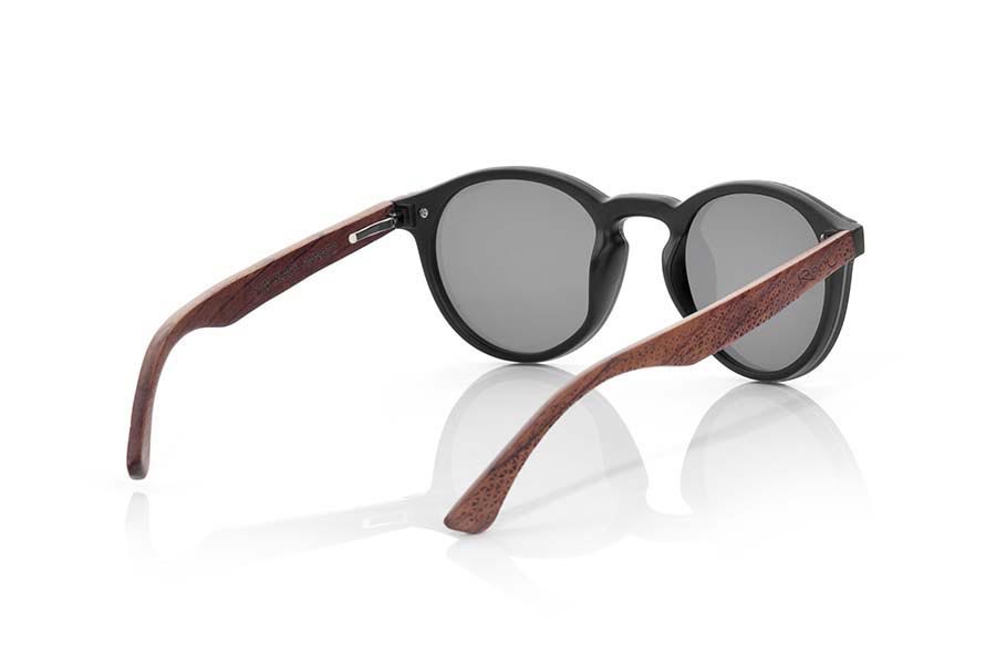 Gafas de Madera Natural de Palisandro SUN BLACK. Las gafas de sol SUN BLACK están realizadas con el frontal de material sintético negro y las varillas en madera de palisandro grabadas con un patrón étnico, se trata de un modelo femenino redondeado muy de tendencia actual las lentes planas <b>PC NO POLARIZADAS</b> cubren todo el frontal.. Medida frontal: 136X49mm Venta al Por Mayor y Detalle | Root Sunglasses® 