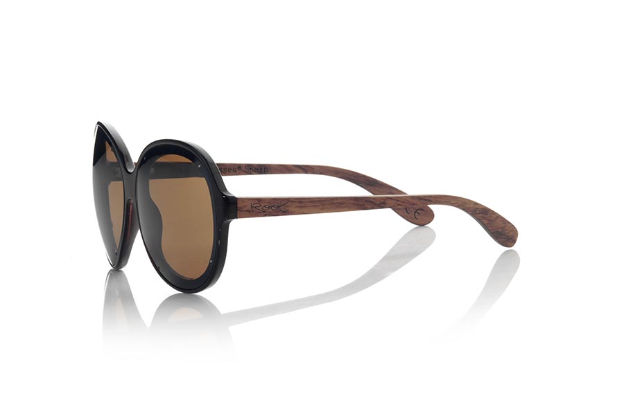 Wood eyewear of Rosewood GUADALMESI. The sunglasses GUADALMESI are made with the front in PC material of glossy black color and the wooden sideburns of rosewood Natural. Very feminine model of suggestive forms inspired by the beaches of GUADALMESI in TARIFA, the GUADALMESI sunglasses have been combined with several lenses. Frontal measurement: 147x60mm for Wholesale & Retail | Root Sunglasses® 