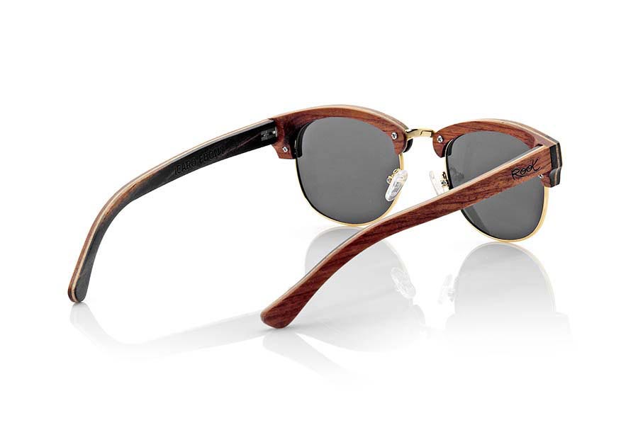 Gafas de Madera Natural de Ébano ICARO. Las gafas de sol ICARO están fabricadas en una combinación de tres maderas, ébano, arce y palisandro combinadas en diferentes capas. el frontal se presenta en madera de ébano una capa intermedia de madera de arce y la parte interior en madera de palisandro mientras que en las varillas se invierte este patrón quedando la madera de palisandro en la parte exterior y la madera de ébano en el interior. Se trata de un modelo unisex abierto con el aro inferior y puente dorado y pads para la nariz ajustables de un tamaño estándar que se adapta a todo tipo de caras y personas. Las hemos combinado con varios tipos de lentes PC. Medida frontal: 143x46mm Venta al Por Mayor y Detalle | Root Sunglasses® 