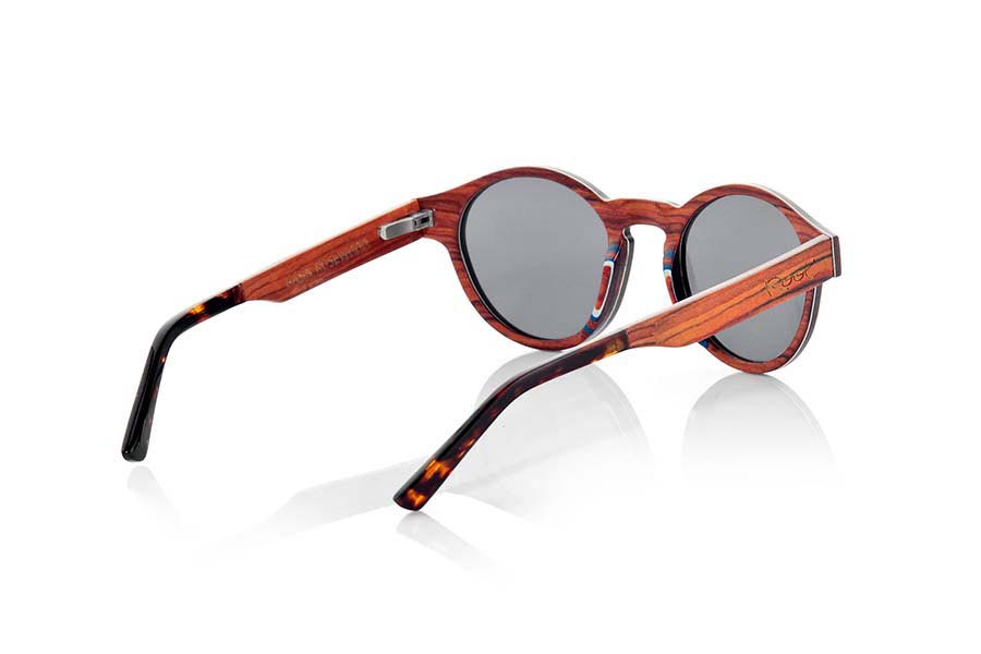 Gafas de Madera Natural de Palisandro BASIN. Las gafas de sol BASIN están fabricadas con finísimas láminas de madera de Palisandro. Incorporan una lámina muy fina de aluminio entre las láminas de madera del frontal además de una lámina coloreada azul. La gafa BASIN es un modelo redondeado con picos marcados a los lados, de un tamaño optimizado para todo tipo de caras tanto de hombres como de mujeres. Las varillas están terminadas en acetato de calidad en color carey lo que permite su ajuste en caso de ser necesario. Las BASIN Son ultra finas con sólo 3.2mm de espesor ultra ligeras sólo 17gr y el refuerzo de aluminio le aporta un plus de resistencia además de un toque metálico en los laterales muy elegante. Te sorprenderá la belleza de la madera su delgadez y su ligereza y comodidad. Las gafas de sol BASIN incluyen  un práctico estuche plegable que mantiene tus gafas seguras cuando están en su interior y ocupa muy poco espacio cuando está plegado. Medida frontal: 141x47mm Venta al Por Mayor y Detalle | Root Sunglasses® 