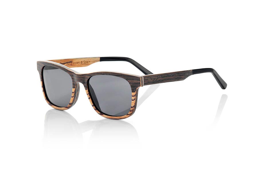 Wood eyewear of Black Walnut NAMIB. NAMIB sunglasses are the result of combining thin sheets of black walnut wood with zebrano wood. The front design is composed of the elegant combination of black walnut wood on the top and zebrawood on the bottom, and the interior of the frame is made of zebranowood. The very thin sheet of aluminum and the blue colored sheet incorporated between the wooden slats on the front add a touch of sophistication. NAMIB glasses are a small, angular model, ideal for thin and tapered faces, with temples finished in high-quality acetate to allow adjustment if necessary. At just 4.2mm thick and weighing 17 grams, they're ultra-thin and ultra-light, but the aluminum reinforcement makes them strong and durable. You will be surprised by the beauty of the combination of two woods on the front and its metallic touch on the sides. In addition, <B>they have a system for mounting prescription lenses</B>. Front measurement: 140x46mm. for Wholesale & Retail | Root Sunglasses® 