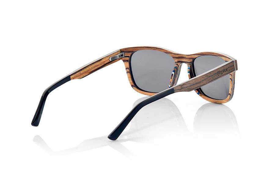 Gafas de Madera Natural de Nogal Negro NAMIB. Las gafas de sol NAMIB son el resultado de la combinación de finas láminas de madera de nogal negro con madera de zebrano. El diseño frontal se compone de la elegante combinación de madera de nogal negro en la parte superior y madera de zebrano en la inferior, y el interior de la montura es de madera de zebrano. La lámina muy fina de aluminio y la lámina coloreada azul incorporadas entre las láminas de madera del frontal aportan un toque de sofisticación. Las gafas NAMIB son un modelo anguloso de tamaño reducido, ideal para caras delgadas y afiladas, con varillas terminadas en acetato de alta calidad para permitir su ajuste en caso de ser necesario. Con solo 4.2mm de espesor y un peso de 17 gramos, son ultrafinas y ultraligeras, pero el refuerzo de aluminio las hace resistentes y duraderas. Te sorprenderá la belleza de la combinación de dos maderas en el frontal y su toque metálico en los laterales. Además, <B>disponen de sistema para montar lentes graduadas</B>.  Medida frontal: 140x46mm. Venta al Por Mayor y Detalle | Root Sunglasses® 