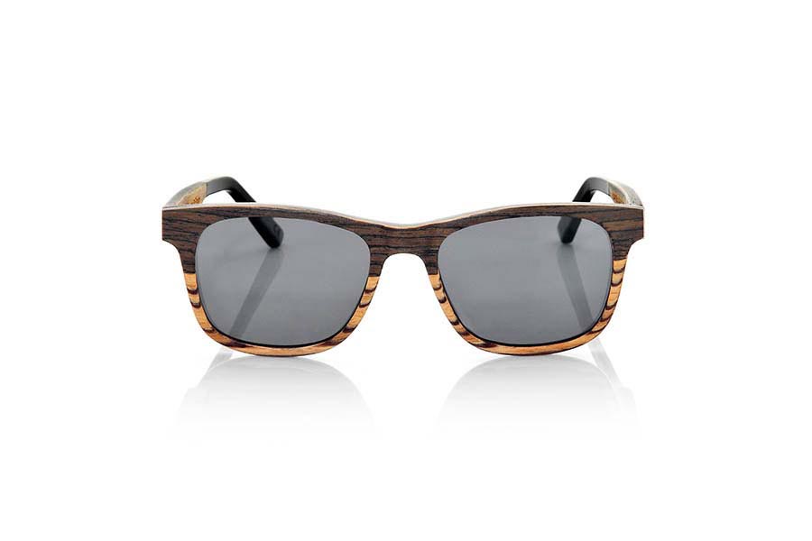 Gafas de Madera Natural de Nogal Negro NAMIB. Las gafas de sol NAMIB son el resultado de la combinación de finas láminas de madera de nogal negro con madera de zebrano. El diseño frontal se compone de la elegante combinación de madera de nogal negro en la parte superior y madera de zebrano en la inferior, y el interior de la montura es de madera de zebrano. La lámina muy fina de aluminio y la lámina coloreada azul incorporadas entre las láminas de madera del frontal aportan un toque de sofisticación. Las gafas NAMIB son un modelo anguloso de tamaño reducido, ideal para caras delgadas y afiladas, con varillas terminadas en acetato de alta calidad para permitir su ajuste en caso de ser necesario. Con solo 4.2mm de espesor y un peso de 17 gramos, son ultrafinas y ultraligeras, pero el refuerzo de aluminio las hace resistentes y duraderas. Te sorprenderá la belleza de la combinación de dos maderas en el frontal y su toque metálico en los laterales. Además, <B>disponen de sistema para montar lentes graduadas</B>.  Medida frontal: 140x46mm. Venta al Por Mayor y Detalle | Root Sunglasses® 