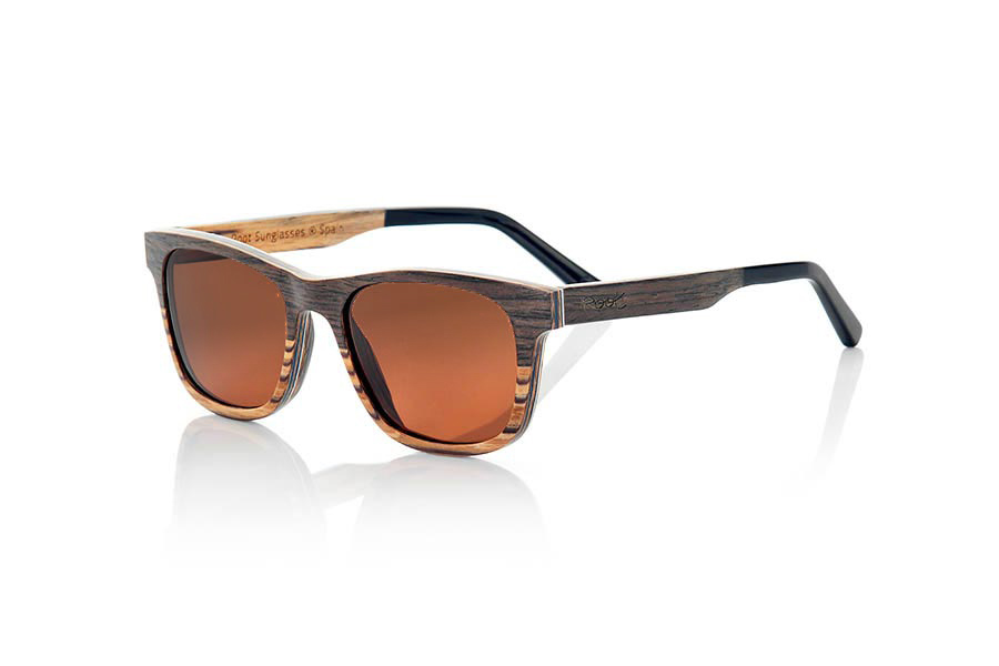 Gafas de Madera Natural de Nogal Negro NAMIB. Las gafas de sol NAMIB son el resultado de la combinación de finas láminas de madera de nogal negro con madera de zebrano. El diseño frontal se compone de la elegante combinación de madera de nogal negro en la parte superior y madera de zebrano en la inferior, y el interior de la montura es de madera de zebrano. La lámina muy fina de aluminio y la lámina coloreada azul incorporadas entre las láminas de madera del frontal aportan un toque de sofisticación. Las gafas NAMIB son un modelo anguloso de tamaño reducido, ideal para caras delgadas y afiladas, con varillas terminadas en acetato de alta calidad para permitir su ajuste en caso de ser necesario. Con solo 4.2mm de espesor y un peso de 17 gramos, son ultrafinas y ultraligeras, pero el refuerzo de aluminio las hace resistentes y duraderas. Te sorprenderá la belleza de la combinación de dos maderas en el frontal y su toque metálico en los laterales. Además, <B>disponen de sistema para montar lentes graduadas</B>.  Medida frontal: 140x46mm. Venta al Por Mayor y Detalle | Root Sunglasses® 