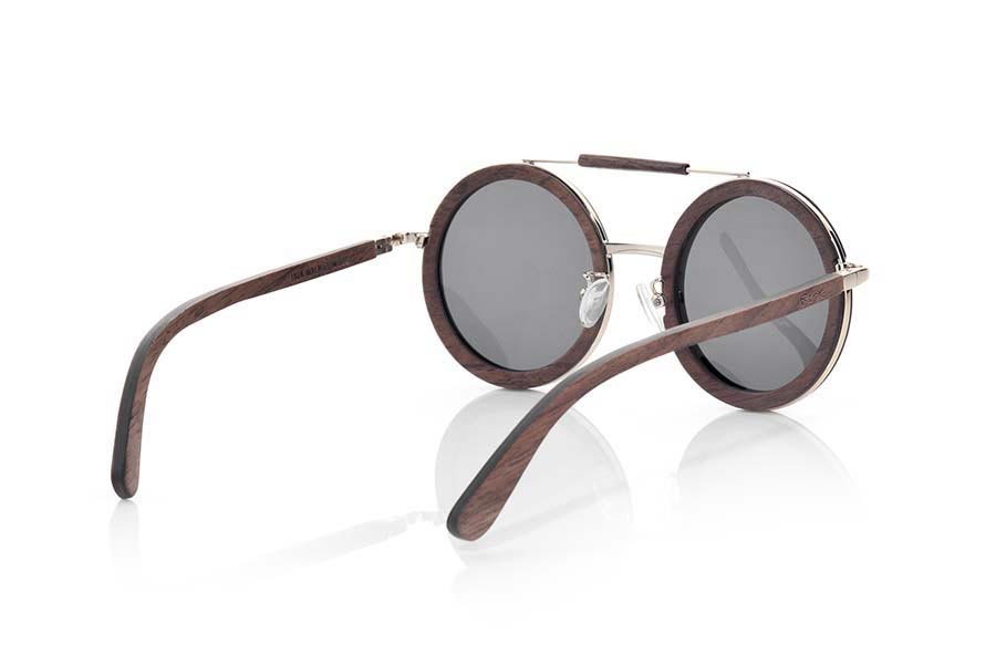 Gafas de Madera Natural de Nogal Negro JAVA. Las gafas de sol JAVA han sido fabricadas en madera de Nogal Negro, es un modelo de formas redonda de estilo boho con una adorno dorado en la ceja revesido de madera de nogal, el contorno de la madera se presenta con aro dorado y las varillas son de nogal negro. Te encantarán su forma, los detalles y la belleza de la madera de nogal. Medida Frontal: 142x57mm Venta al Por Mayor y Detalle | Root Sunglasses® 