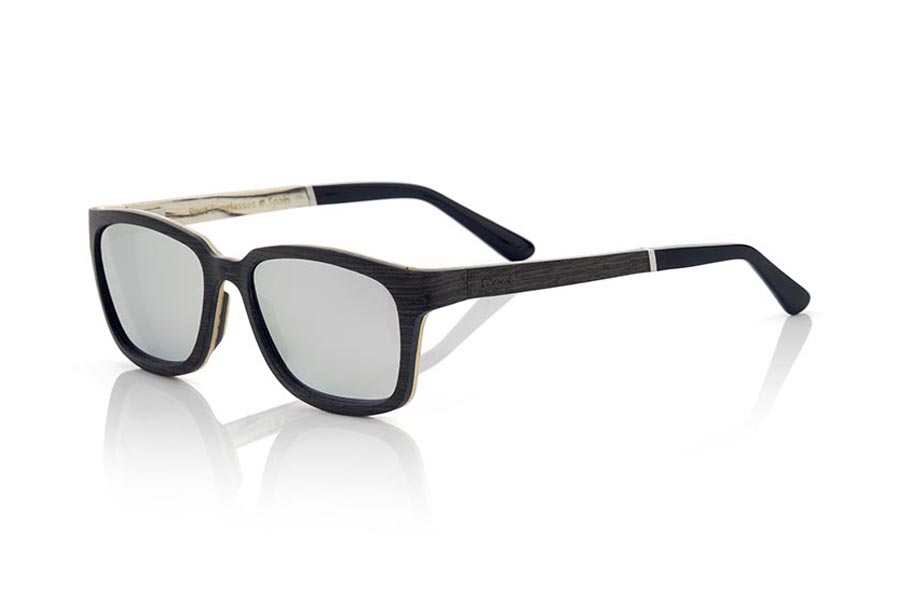 Gafas de Madera Natural de Mpingo modelo MADEIRA. Las gafas de sol de madera MADEIRA son un modelo de vanguardia fabricado en madera de ébano y white wood, con una estructura laminada de formas sugerentes y líneas modernas. La bisagra de las patillas se presenta adelantada, lo que le da un toque innovador y arriesgado. El frontal de las MADEIRA está fabricado con madera laminada de Mpingo en el exterior y white wood en el interior, lo que aporta una belleza única a las gafas. Las patillas también están realizadas con el mismo esquema laminado que la montura y terminan en acetato con varilla que permite ser ajustado en caso necesario. Las MADEIRA son un modelo elegante y sofisticado que sorprenderá a todos por su combinación de maderas, cuidada terminación y su forma tan sugerente. Medida frontal: 138x45mm. | Root Sunglasses®