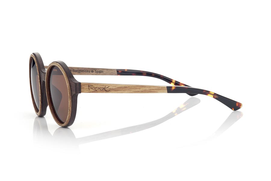 Gafas de Madera Natural de Walnut NILIA. Las gafas de sol NILIA están fabricadas en una combinación de dos maderas, Nogal negro en montura y roble en aro exterior de la montura y varillas. estas ultimas están terminadas en acetato carey con varilla interna lo que permiten ser ajustadas en caso de ser necesario.  Se trata de un modelo redondeado con personalidad propia con una terminación muy cuidada. Medida frontal: 140x50mm Venta al Por Mayor y Detalle | Root Sunglasses® 