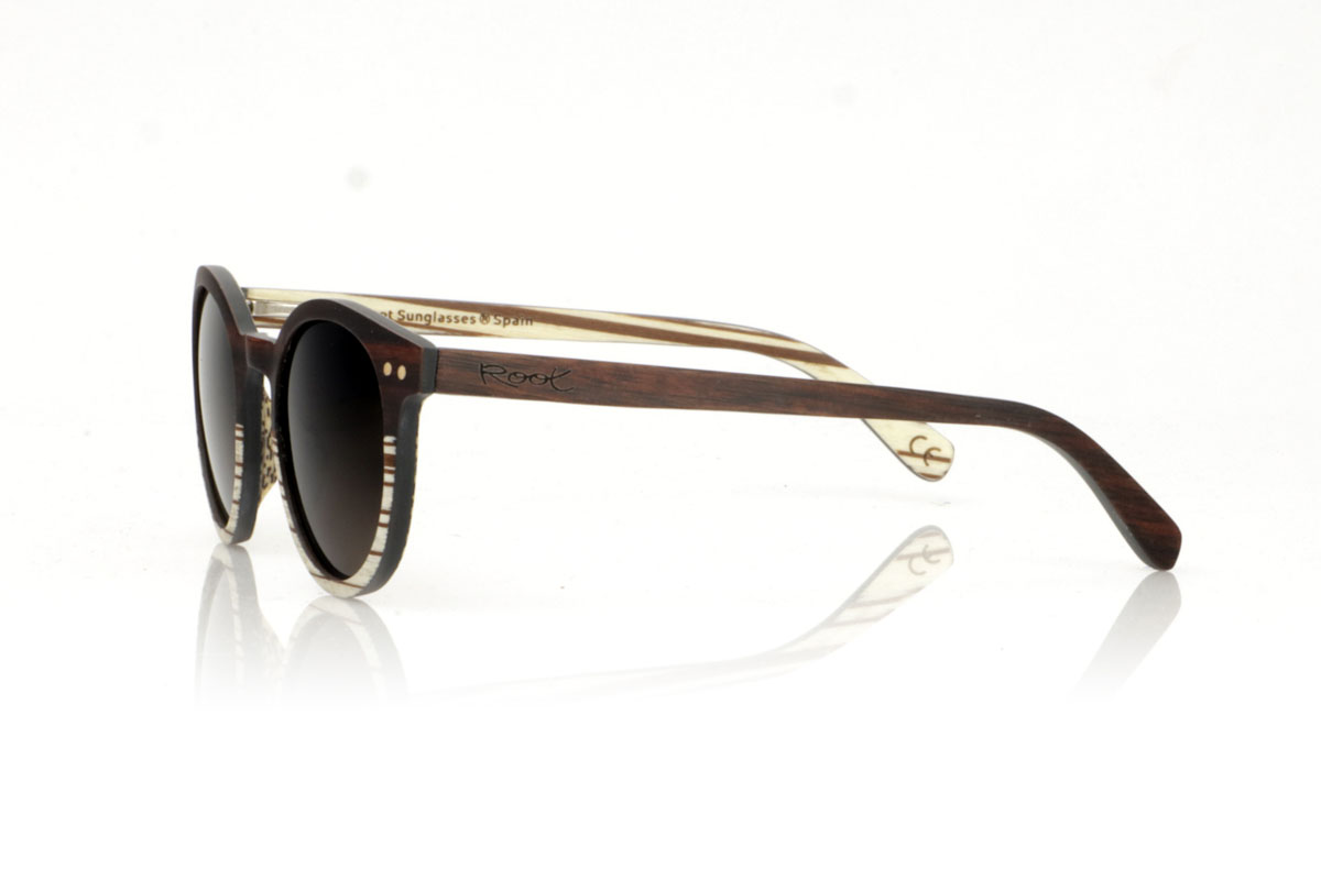 Wood eyewear of Ebony ATHENEA. ATHENEA wooden sunglasses, with their compact and rounded design and a pronounced eyebrow similar to the LANA and LINDA models, stand out for their elegance and originality. Made with a unique combination of ebony wood on the top of the front and white zebra on the bottom, these glasses offer a stunning visual contrast that captures attention. Additionally, the front is enriched with two round beech wood inlays, adding a distinctive detail and a touch of sophistication. Measuring 135x47mm and with a caliber of 45, the ATHENEA are ideal for those looking for smaller glasses without sacrificing style or presence. for Wholesale & Retail | Root Sunglasses® 