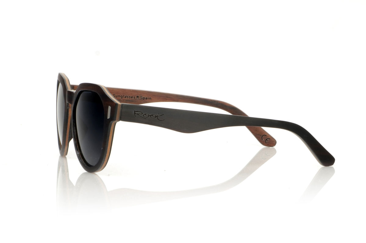 Wood eyewear of Ebony IZARO. IZARO wooden sunglasses are an expression of style and craftsmanship, made entirely of laminated ebony wood both outside and inside, with an intermediate layer of maple wood that provides a clear and striking contrast. The distinctive black and brown grain of the ebony is perfectly complemented by the distinctive hexagonal shape on the brow, while the silver metallic inlays on the sides add a touch of elegance and sophistication. With measurements of 145x50 and a caliber of 51, the IZARO are presented as a perfect option for those looking to stand out with a unique accessory that combines the natural beauty of wood with an innovative design. for Wholesale & Retail | Root Sunglasses® 