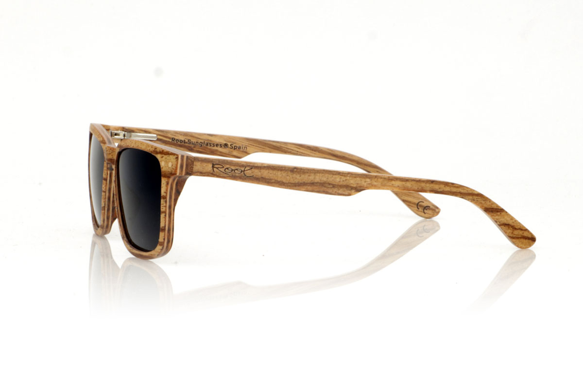 Wood eyewear of Zebrano ROMUALD. ROMUALD wooden sunglasses stand out for their design, entirely made of light-colored laminated zebrawood with a marked grain, which gives them a distinctive and natural presence. Its more square shape adapts perfectly to smaller faces, offering a balanced and attractive aesthetic. Round maple wood inlays on the front add delicate detail. With measurements of 135x41 and a caliber of 50, these glasses are ideal for those looking for an accessory with personality and style. for Wholesale & Retail | Root Sunglasses® 