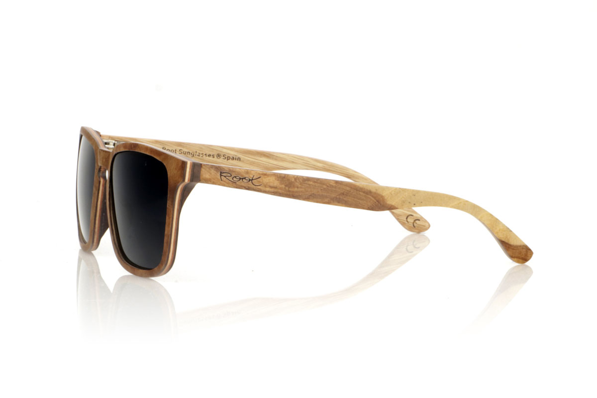 Wood eyewear of Burr OLIVER. OLIVER wooden sunglasses, medium in size and with a square shape with rounded and soft lines, are the perfect balance between design and nature. Made with a careful lamination of olive wood on the outside and interspersed with layers of beech wood, they stand out for the warm color and unique grain that olive wood offers. This combination not only provides exceptional resistance, but also makes each pair a unique piece. With a measurement of 145x47 and a caliber of 53, the OLIVER adapts wonderfully, offering comfort and unmistakable style to those who wear them. Ideal for those looking to stand out with an accessory that speaks of elegance and commitment to the environment. for Wholesale & Retail | Root Sunglasses® 