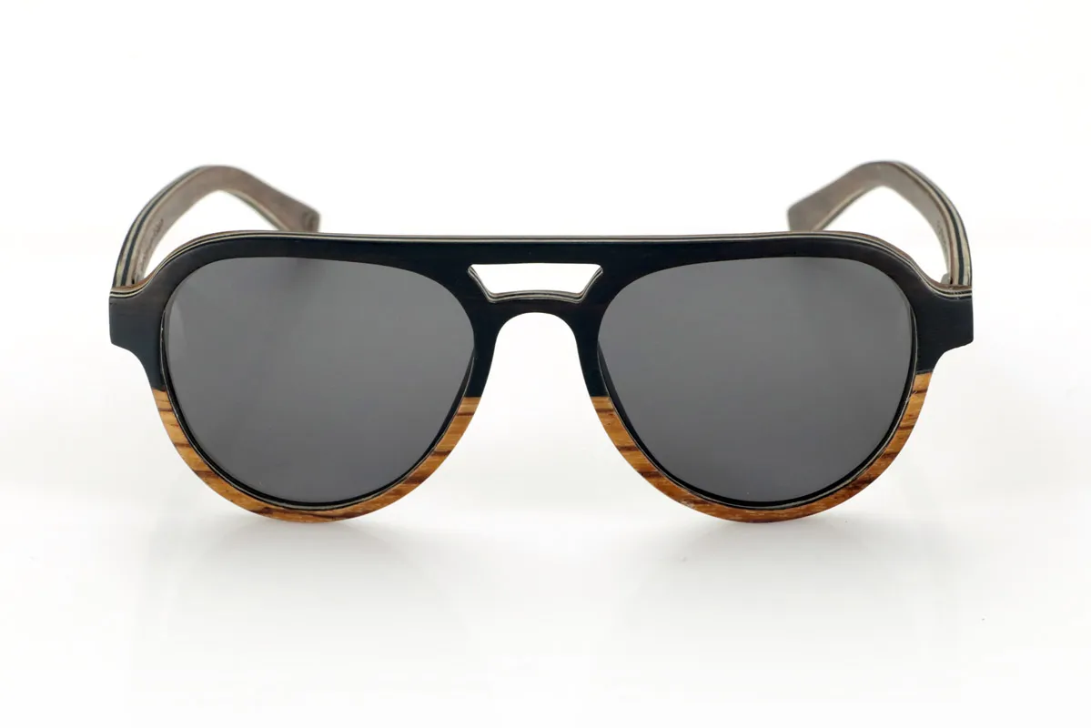 Wood eyewear of Ebony FLYER SK. FLYER SK sunglasses are handcrafted entirely from laminated wood, combining ebony, walnut and zebrawood. Their aviator-inspired design maintains a classic aesthetic with a distinctive bridge, providing a balance between style and functionality.
The laminated wood structure enhances the natural grain of each material, providing an organic and lightweight finish. Thanks to its layered construction, this model offers strength and comfort for daily use.
High-quality polarized lenses guarantee total UV protection and reduce glare, improving visual clarity. A timeless design that connects with nature without sacrificing protection and comfort.
Dimensions 144x52mm. Caliber 53. for Wholesale & Retail | Root Sunglasses® 