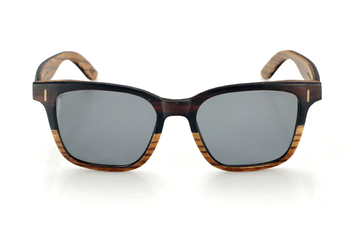 Gafas de Madera Natural de mpingo LOREA. Las gafas de sol LOREA están fabricadas en una combinación de dos maderas, Mpingo (African Black wood) en parte superior de montura y en el exterior de las varillas y Zebrano en la parte inferior de la montura y en el interior de las varillas.  Se trata de un modelo fácil de llevar sencillo y elegante con una terminación muy cuidada que te sorprenderá por su originalidad y la combinación de maderas. Medida frontal: 145x50mm Venta al Por Mayor y Detalle | Root Sunglasses® 